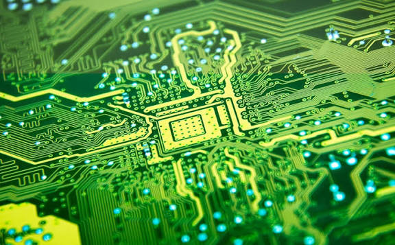 Close-up of a green printed circuit board with illuminated traces